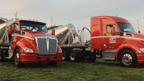 Two red semis with attached hopper trailers